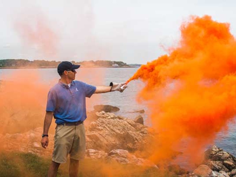 Man deploying orange smoke flare